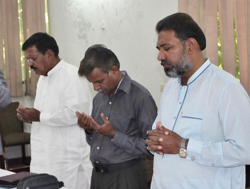 Three Pakistanian men are standing with their eyes closed and hands folded in prayer to God