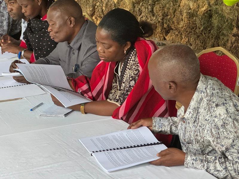 Adult people are sitting at a table, studying. They are students of a Bible training program in Tanzania